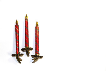 Christmas tree decorations. Three glass red-green candles with a golden flame on metal clothespins on a white background. Copy scape for your text.