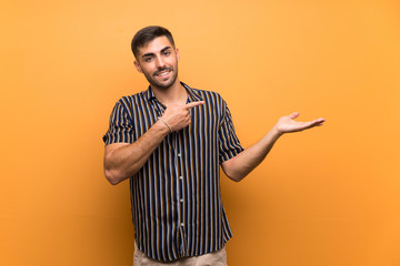 Handsome man with beard over isolated background holding copyspace imaginary on the palm to insert...