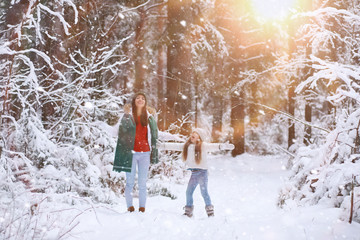 Young family for a walk. Mom and daughter are walking in a winter park.