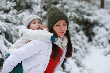 Young family for a walk. Mom and daughter are walking in a winter park.