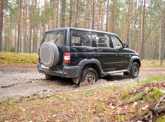 Obraz na płótnie Canvas black jeep SUV driving on abandoned sand road in forest