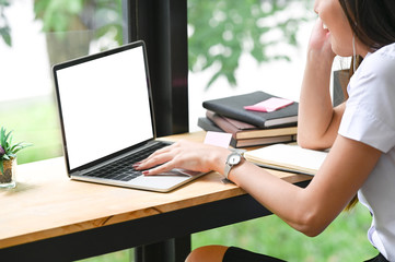 Young Thai university student using mockup laptop in co working space.