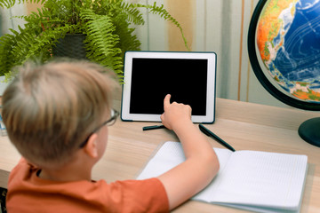 a young boy in glasses shows a finger at the black blank screen of the tablet. place for your content or text. selective focus