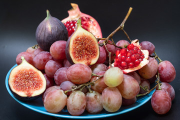 Grapes, figs and pomegranate on a dark background