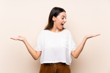 Young brunette woman over isolated background holding copyspace with two hands