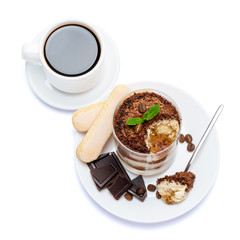 Classic tiramisu dessert in a glass, cup of coffee and pieces of chocolate on white background with clipping path