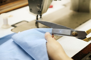 Close up hands cutting fabric with scissors for sewing clothes 