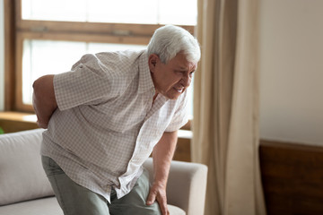 Senior man got up from couch felt low back pain