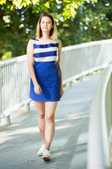 Obraz premium Woman in fashion dress walking along city bridge