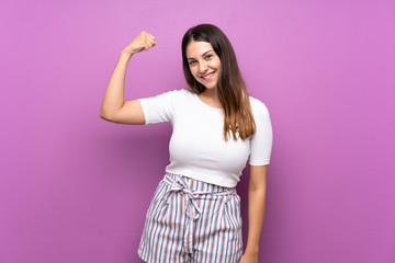Young woman over isolated purple background doing strong gesture