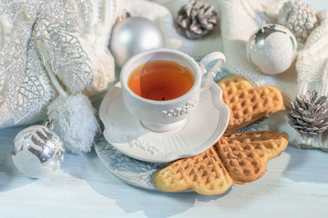 Winter, Christmas balls, a hot steaming cup of tea and a warm sweater on a wooden table background.