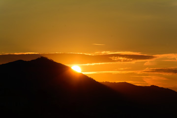 Silhouette di monti all'alba con il sole che fa la sua comparsa dietro di loro