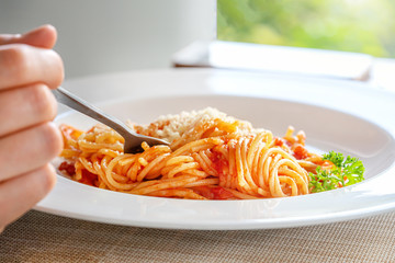 Female hand holds a fork with spaghetti. Breakfast or dinner outdoors, close-up