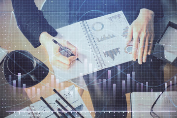 Multi exposure of hands making notes with forex chart huds. Stock market concept.