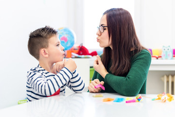 Children speech therapy concept. Preschooler practicing correct pronunciation with a female speech therapist. - obrazy, fototapety, plakaty