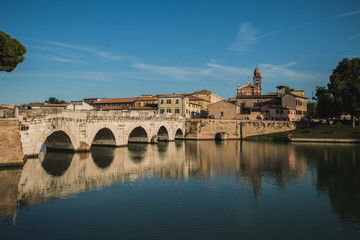 Fototapeta premium Rimini, Italy - September 11, 2019: Tiberius bridge in Rimini on a background of blue sky with white clouds