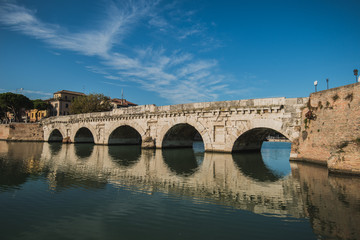 Rimini, Italy - September 11, 2019: Tiberius bridge in Rimini on a background of blue sky with...