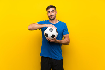 Young handsome football player man over isolated yellow wall