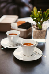 Close up. The small white ceramic mug (cup) with Italian espresso (coffee) on a table with a saucer and a metal spoon in a local Italian bar (coffee shop) in Milan, Lombardy, Italy. Beverage.