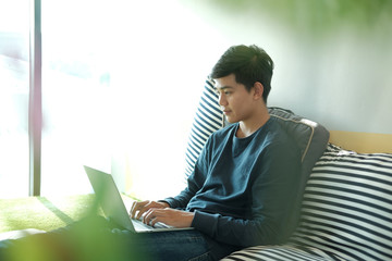 man sitting on floor using computer at home. male teenager student studying doing assignment