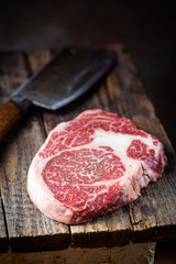 Raw fresh meat Ribeye Steak and seasonings on wooden background, rustic style
