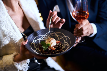 High european cuisine. People eat sweet dessert from beautiful dish and drink red champagne. Restaurant concept