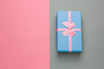 top view blue gift box with festive pink bow on a gray background with pastel pink frame with free space for text