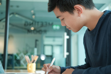 Fototapeta premium man writing reminder note. male freelancer student working organizing plan at workplace