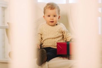 Little boy sitting on bench outside in Christmas time. Happy child