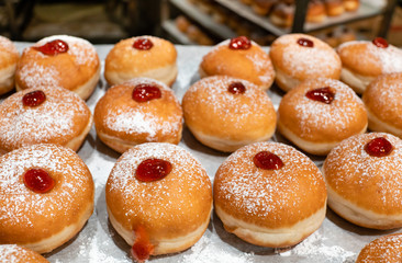 Fresh donuts  with jelly at the bakery display for Hanukkah celebration. Selective focus.