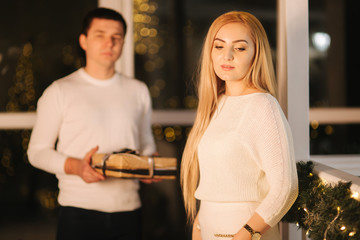 Husband gives present for his wife, background of window. Happy woman take present