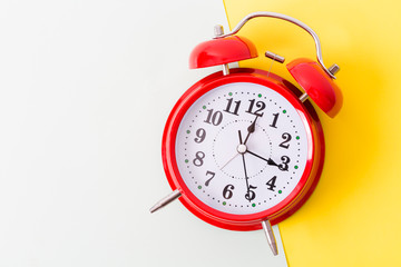 Red vintage alarm clock on yellow background