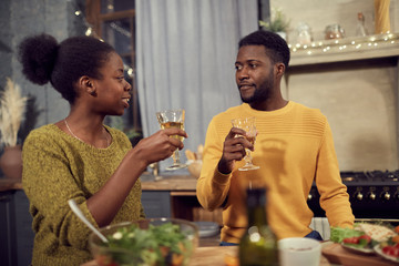 Waist up portrait of young African-American couple drinking wine while enjoying dinner at home, copy space