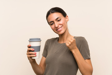 Young woman holding a take away coffee celebrating a victory