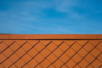 Natural orange roof tiles on a building against blue sky.