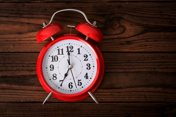 Red alarm clock on wooden table, time to wake up