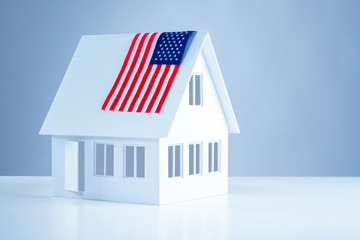 Miniature cottage with US flag. American flag on the roof. Green card. Acquisition of real estate...