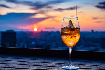 Filled glass against the sunset. The glass stands on the dark windowsill. The light of the setting sun is reflected in the glass. Rest. Relaxation. Calm. Pleasure.