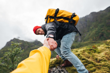 Group of two active tourist with backpack climb to rock helping each other. Brave traveler hold hand his friend for helping climb to mountain lifestyle outdoor journey