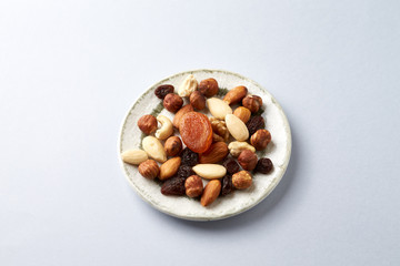 Nuts, raisins and apricots on bright paper background. Concept for healthy snack. Copy space. 