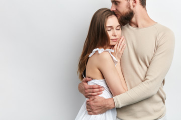 man is hugging his wife, holding in tighet hug, close up cropped phdoto. tender feeling and emotion . copy space, isolated white background