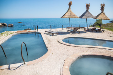 Fototapeta premium Blue water pools and straw umbrellas