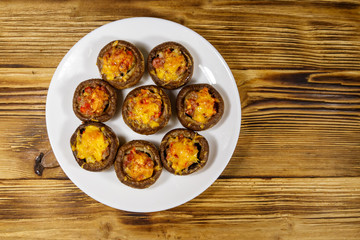 Baked mushrooms stuffed with minced meat, mushroom, paprika, onion and cheese on wooden table. Top view