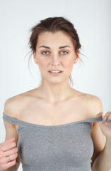 Young beautiful girl in a gray t-shirt on a white background looks at the camera and smiles