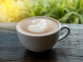 latte coffee with beautiful steamed milk art in white mug on wooden table  in the garden,