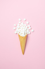Waffle cone with white mini marshmallows on a pink background Top view Flat lay Copy space