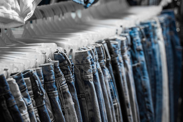 Fashion pants and jeans on the rack in clothing store. Sale, shopping, fashion, style concept. Jean Pants Hang on Shelf . Close up shot Vintage Denim jeans stack on shelves collection in store.