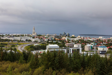 Fototapeta na wymiar A cityscape of Reykjavík, the capital and largest city of Iceland, photographed from a hill on a cloudy summer day.