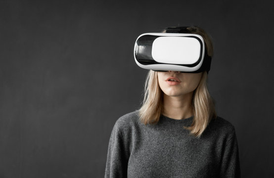 Fototapeta Young woman wearing virtual reality goggles headset, vr box. Connection, technology, new generation, progress concept. Girl trying to touch objects in virtual reality.