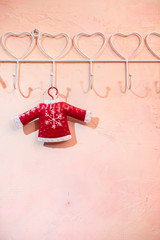 Red Santa Clause sweater with snowflake hooked on pink wall
